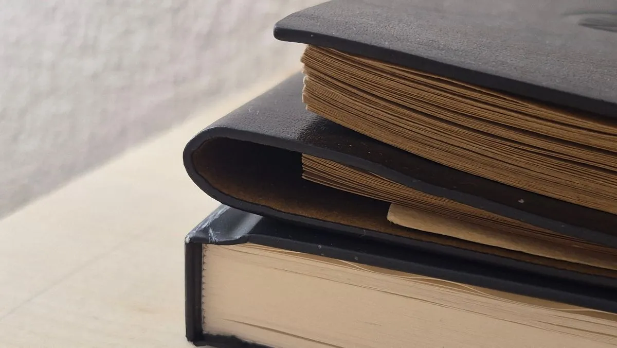 A stack of worn hardcover books on a desk.
