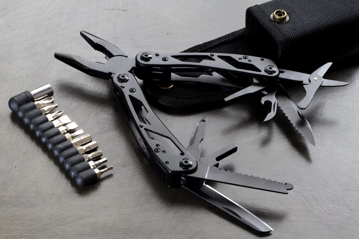 A black folding multi-tool opened out beside a row of screwdriver bits and a belt pouch.