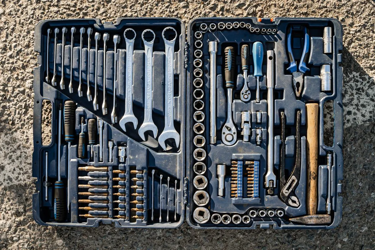 An open tool case laid out with spanners, screwdrivers, sockets and a hammer.